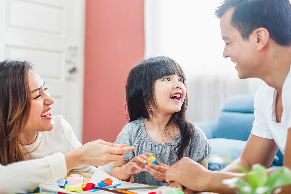 Girl daughter playing blocks toy over father and mother, happy family concept